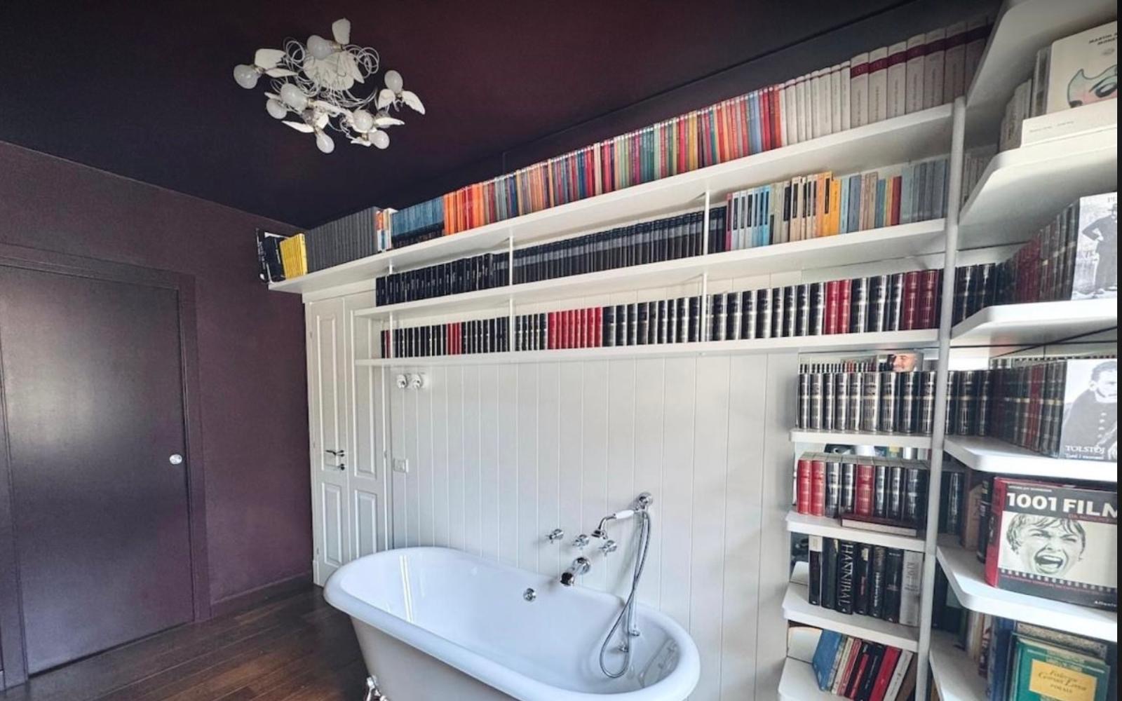 Stanza relax: vasca freestanding davanti alla libreria